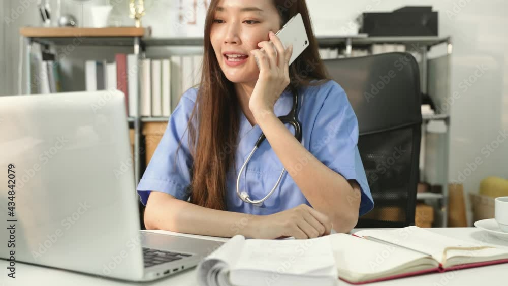 Asian female doctor or nurse using mobile phone with laptop during work in the clinic. Asian female doctor or nurse using mobile phone with laptop during work in the clinic.
