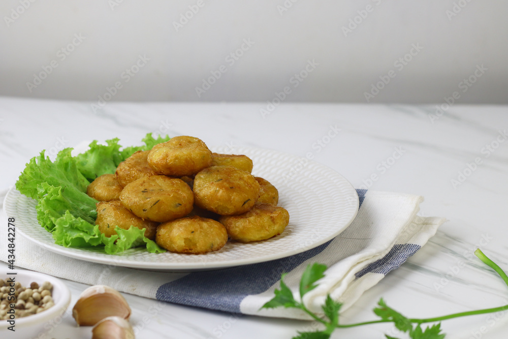 Perkedel Kentang or Potato cutlet, one of Indonesian food made from mashed potato, celery, spice, and fried. White marble background, copy space for text Perkedel Kentang or Potato cutlet, one of Indonesian food made from mashed potato, celery, spice, and fried. White marble background, copy space for text