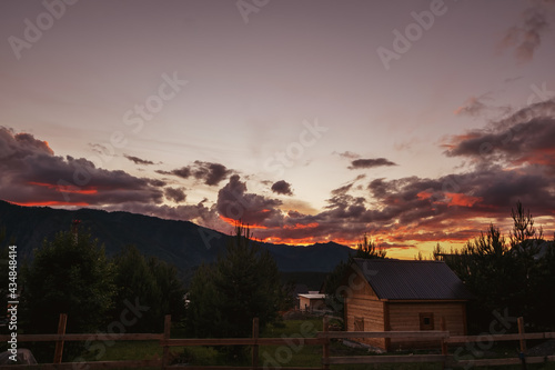 Beautiful red sunset above mountains village wooden home