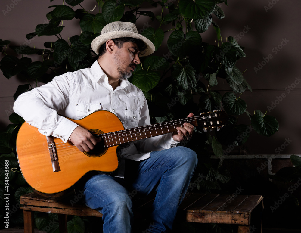 Obraz premium Músico cubano con sombrero en una plaza en la noche ejecutando una guitarra española
