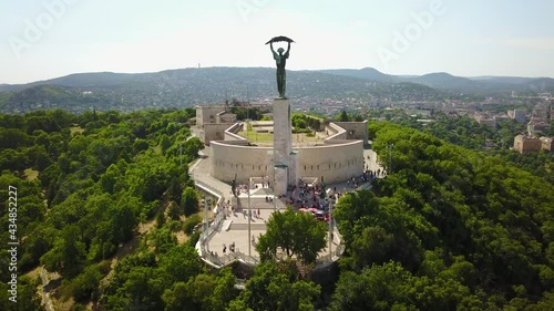 Cinematic aerial orbiting drone footage of the Liberty Statue, Szabadság szobor, a memorial on Gellért Hill at the Citadella fortress with Buda Castle and the Danube river in Budapest, Hungary photo