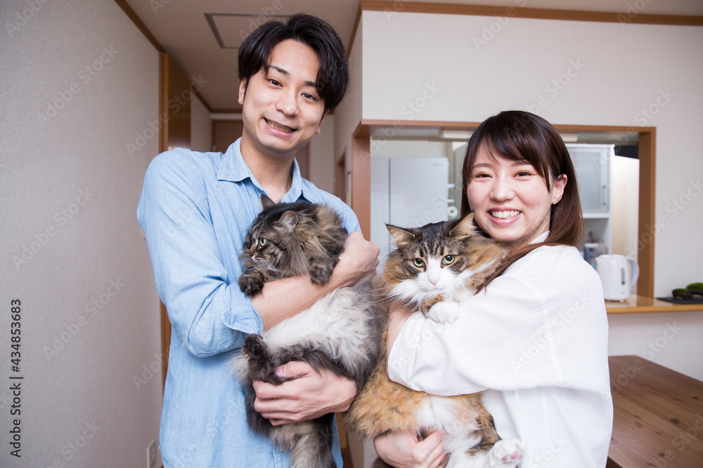 自宅でペットの猫を抱く日本人の若いカップル Stock Photo Adobe Stock