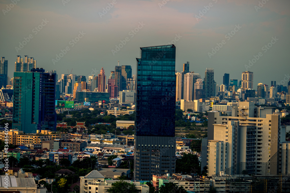 Panorama background of city views, with colorful twilight sky, high-rise buildings (condominiums, offices, expressways) and blurred lights from roads and traffic.