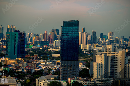 Panorama background of city views, with colorful twilight sky, high-rise buildings (condominiums, offices, expressways) and blurred lights from roads and traffic. © bangprik