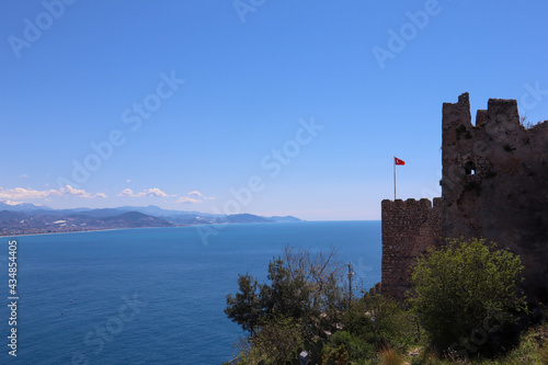 turkish flag on the wall of the medieval Alanya fortress with azure sea on the background