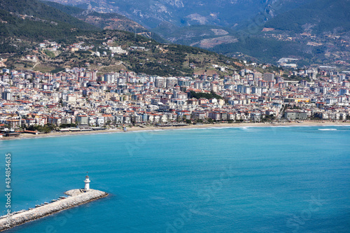 white lighthouse on the pier in Alanya port in Turkey surrounded by azure water of mediterranean sea