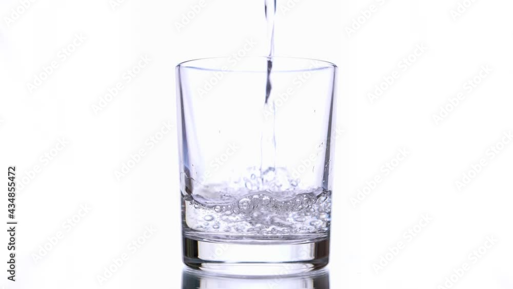Slow motion macro still life of water poured in transparent glass isolated on white background Slow motion macro still life of water poured in transparent glass isolated on white background