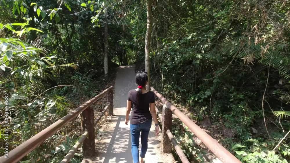 Young Asian lady lady walking across a wooden bridge in Khao Yai National Park Thailand Young Asian lady lady walking across a wooden bridge in Khao Yai National Park Thailand