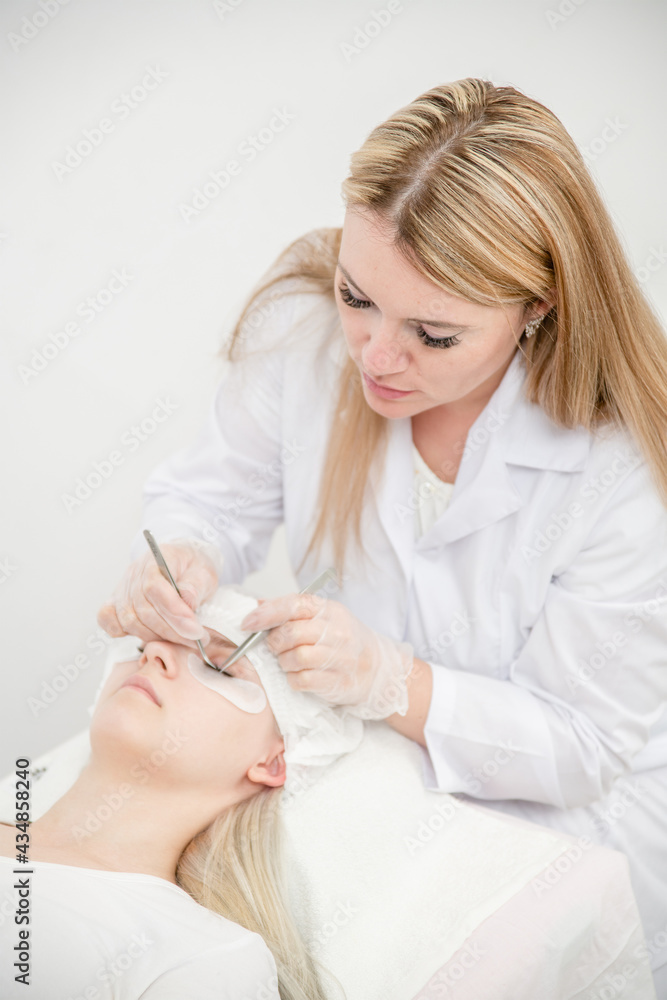 Professional cosmetologist lengthening female lashes in beauty salon Professional cosmetologist lengthening female lashes in beauty salon