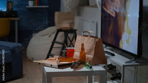 Close up of table with food and booze leftover on misery table in empty unorganized dirty living room of depresive alone person. Untidy house apartment of woman with sever depresion photo