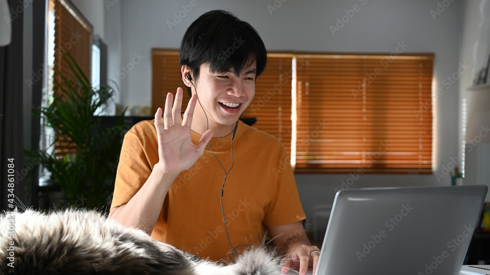 Happy man waving hand greeting his colleagues during video call on laptop. Happy man waving hand greeting his colleagues during video call on laptop.