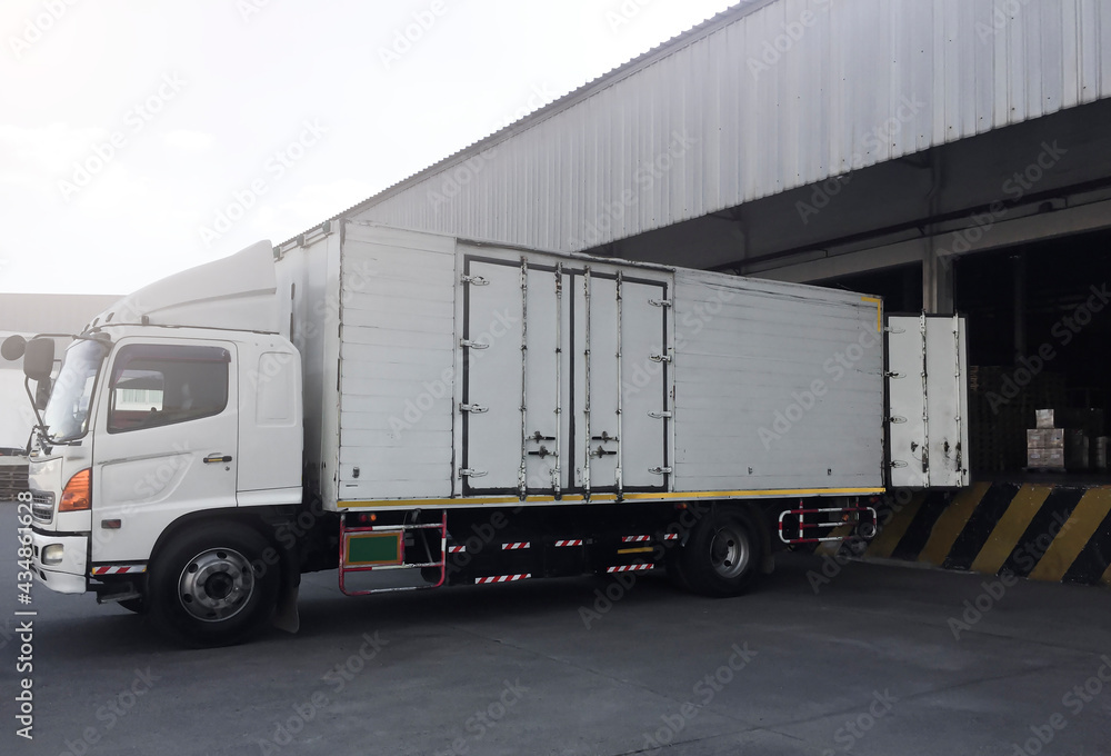 Fototapeta premium Cargo Container Truck Parked Loading at Dock Warehouse. Cargo Shipment. Industry Freight Truck Transportation. Shipping Warehouse Logistics.