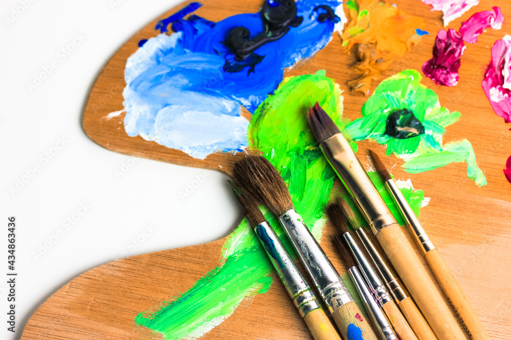 Fototapeta premium Wooden palette for mixing paints, brushes close-up. Creativity, art concept.