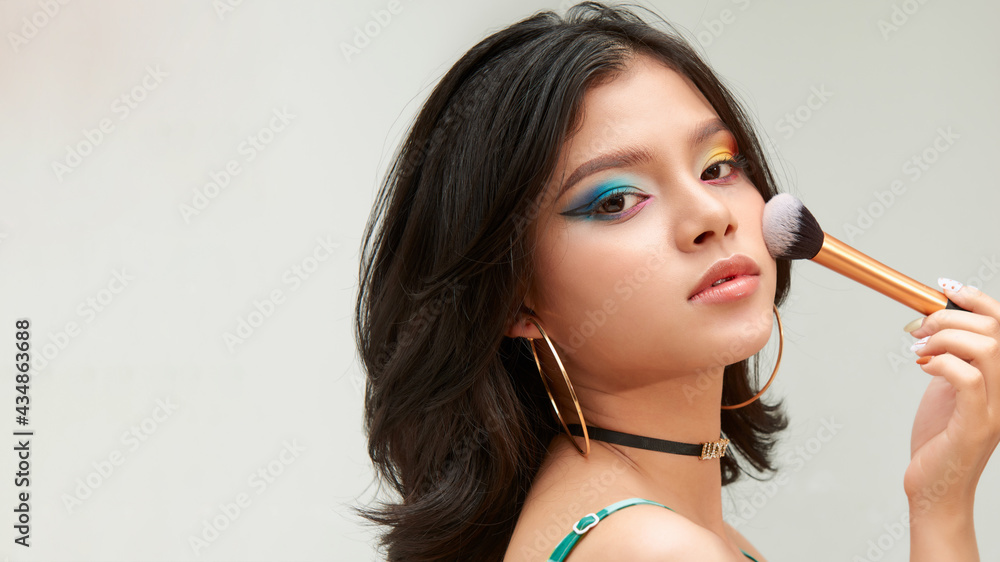 Closeup portrait of a woman applying dry cosmetic tonal foundation on the face using makeup brush Closeup portrait of a woman applying dry cosmetic tonal foundation on the face using makeup brush