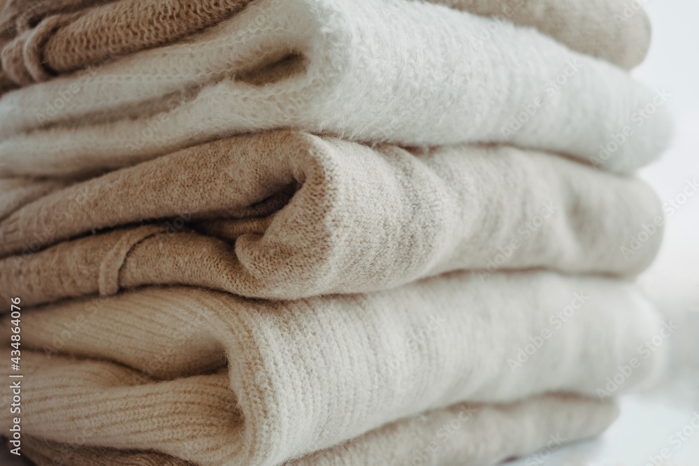 cozy milky beige and white natural wool sweaters, folded on a white background close-up. clothes made of merino wool, alpaca, natural eco-fabrics. the concept of conscious consumption. mockup cozy milky beige and white natural wool sweaters, folded on a white background close-up. clothes made of merino wool, alpaca, natural eco-fabrics. the concept of conscious consumption. mockup
