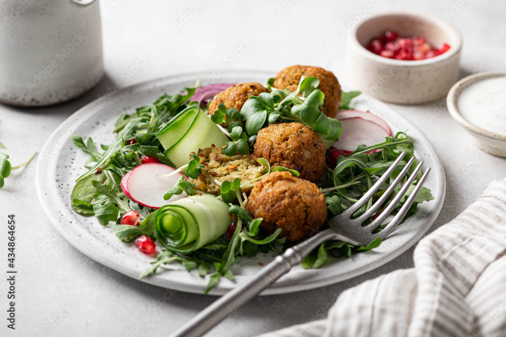 Falafel and fresh vegetables salad on a white ceramic plate on concrete background, selective focus. Falafel and fresh vegetables salad on a white ceramic plate on concrete background, selective focus.