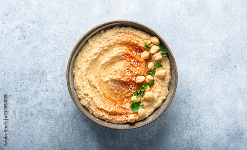 hummus in a ceramic bowl on a blue background, top view, copy space photo