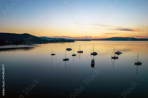 Sunrise waterscape with boats, light cloud and reflections © Merrillie