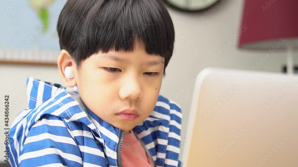 Online learning programs concept. Portrait of a cute and smart asian student boy with wireless earbuds using tablet computer to join online classroom from home during Covid-19 pandemic. New normal. Online learning programs concept. Portrait of a cute and smart asian student boy with wireless earbuds using tablet computer to join online classroom from home during Covid-19 pandemic. New normal.