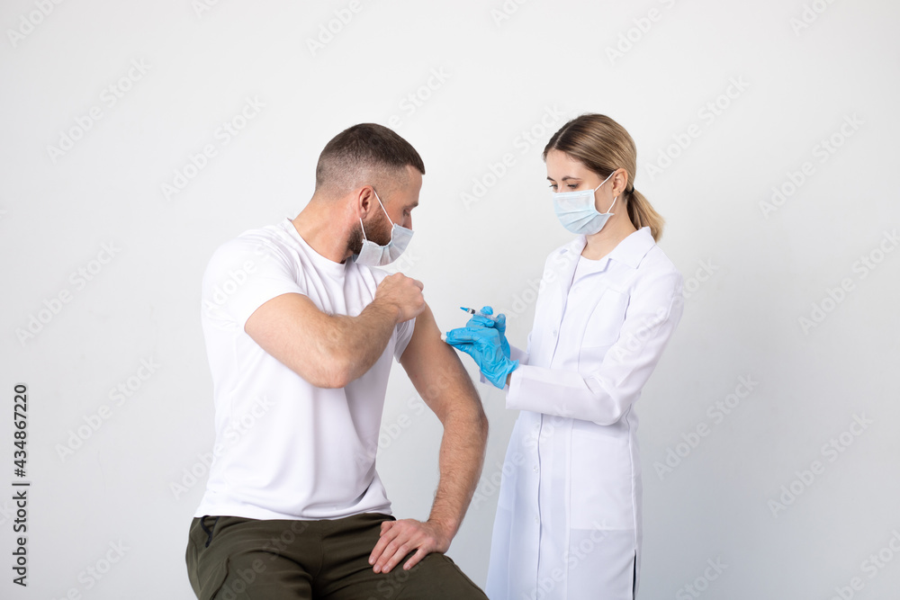 Woman doctor giving the patient a man in a medical mask an injection of the covid-19 vaccine. Woman doctor giving the patient a man in a medical mask an injection of the covid-19 vaccine.