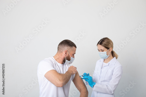 Woman doctor giving the patient a man in a medical mask an injection of the covid-19 vaccine.