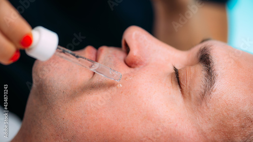 Fototapeta Naklejka Na Ścianę i Meble -  Cosmetician Applying Hyaluronic Acid Serum on Man’s Face