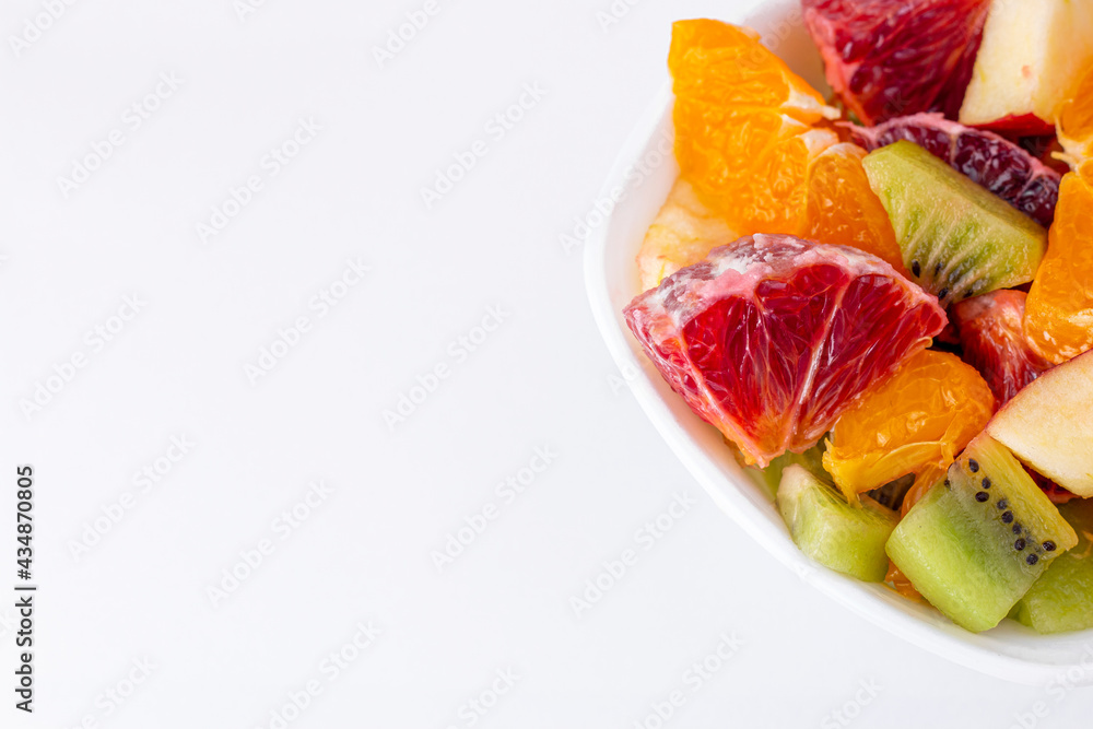 Fruit salad in ceramic bowl isolated on white background Delicious cut fruits close up background. Grapefruit, orange, kiwi and apple.