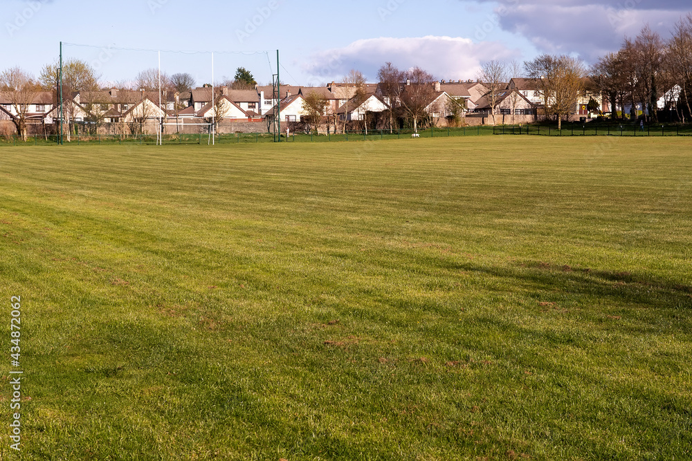 Irish National sport goal post on a training ground. Camogie, hurling, rugby, gaelic football pitch. Warm sunny day, Cloudy sky. Houses in the background Irish National sport goal post on a training ground. Camogie, hurling, rugby, gaelic football pitch. Warm sunny day, Cloudy sky. Houses in the background