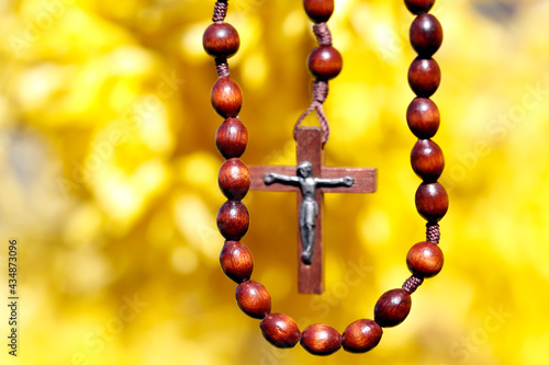 Wooden rosary against yellow broom flowers.