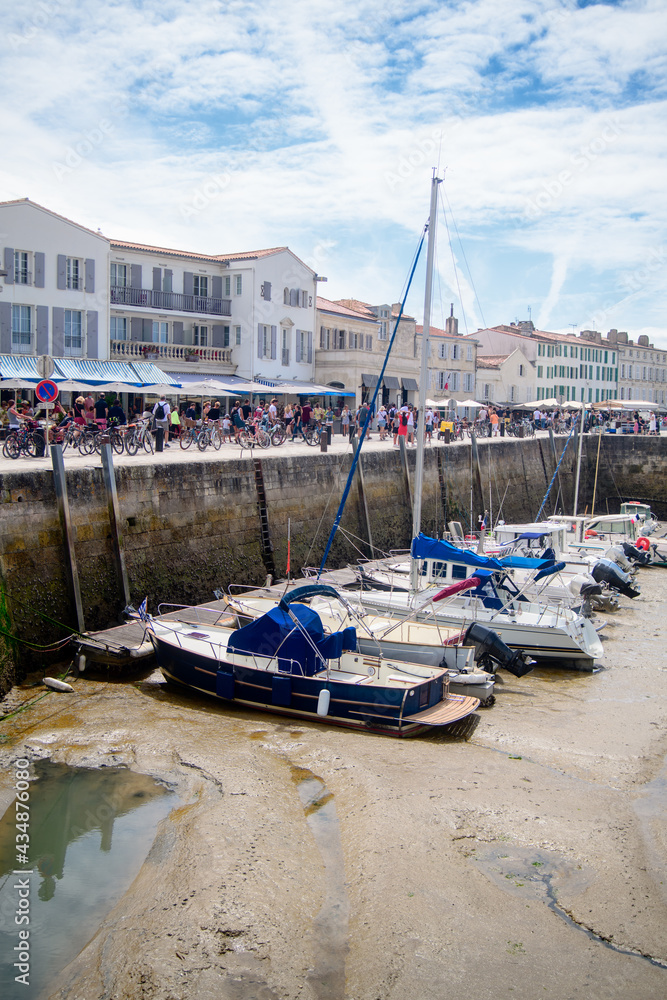 View on the harbor of Saint-Martin-de-Ré at lowtide with boats and people walking on a sunny summerday