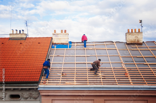 three builders replace the tiled roof in the old town