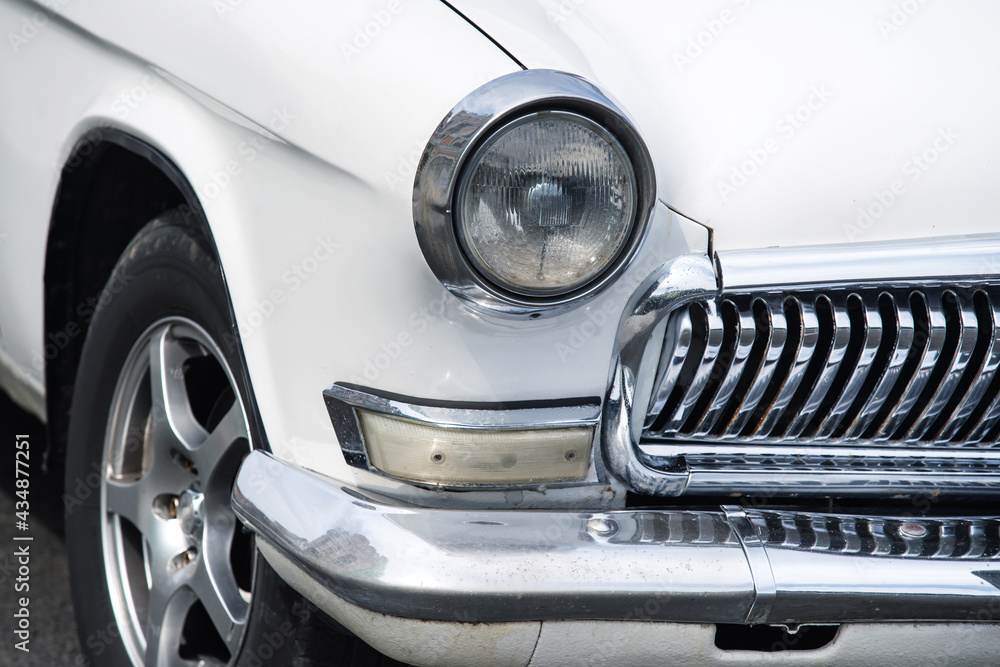 Fragment of a retro car with a headlight and chrome details. Close-up