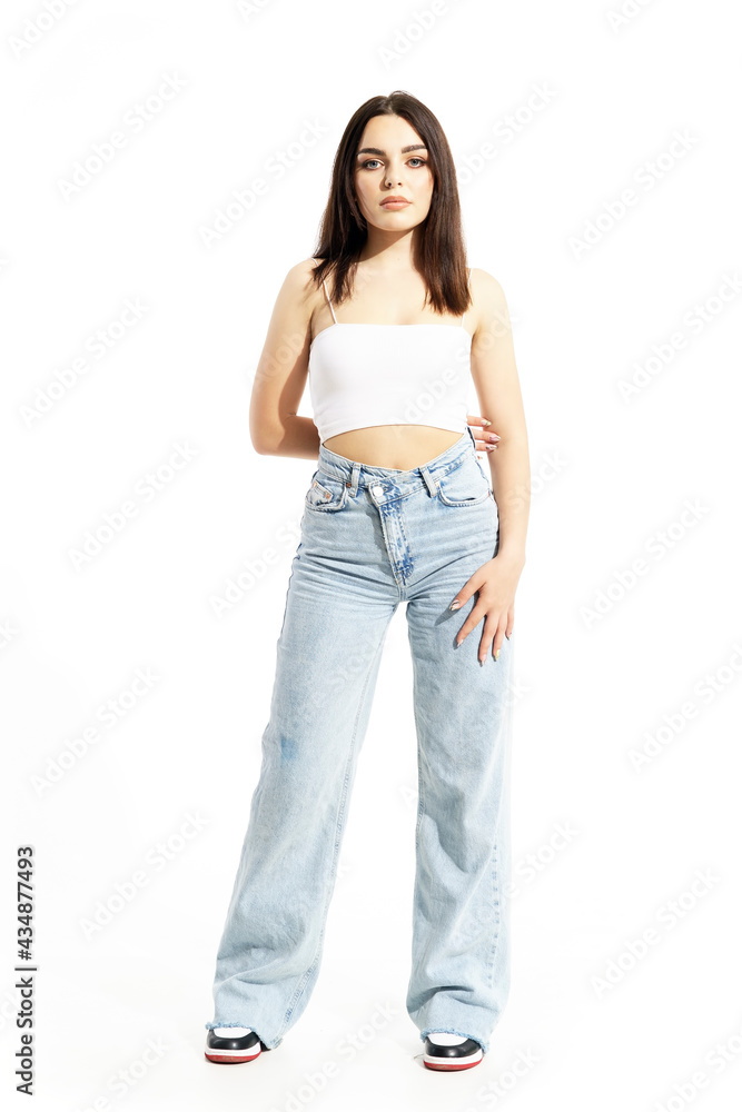 Cute beauty young woman in trendy summer street style clothes holding arm behind back. Full body length isolated on white background Cute beauty young woman in trendy summer street style clothes holding arm behind back. Full body length isolated on white background