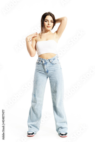 Lovely feminine young woman holding hair in ponytail posing in summer street clothes. Full body length isolated on white background
