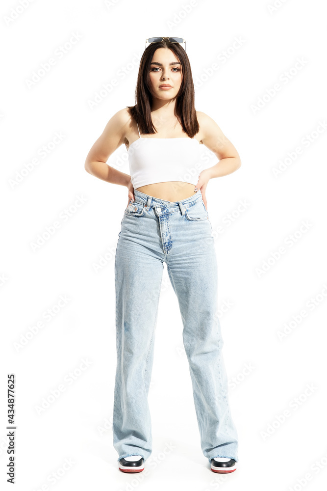 Beautiful young stylish woman in hard sunny summer light posing with hand on hips. Full body length isolated on white background Beautiful young stylish woman in hard sunny summer light posing with hand on hips. Full body length isolated on white background