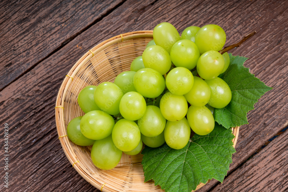 Japanese Shine Muscat Grape in basket on wooden Background, Sweet Green grape on wooden background. Japanese Shine Muscat Grape in basket on wooden Background, Sweet Green grape on wooden background.