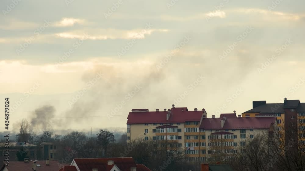 Thick black smoke rising up between buildings in residential area. Thick black smoke rising up between buildings in residential area.