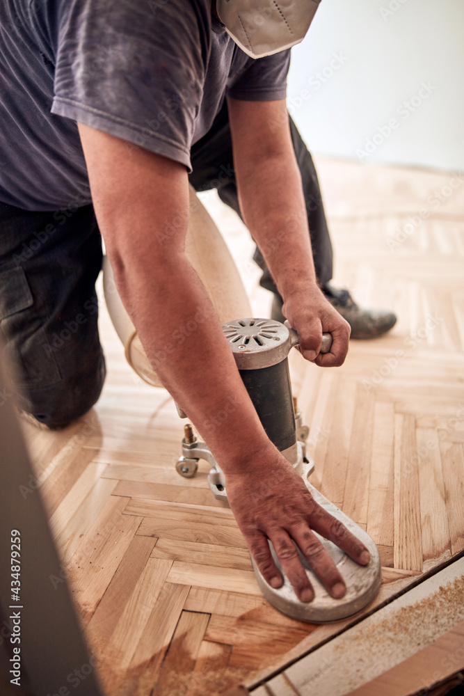 Repairman restoring parquet with a sanding machine. Repairman restoring parquet with a sanding machine.