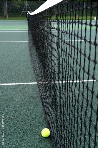 view of tennis net and ball in local outdoor tennis court.