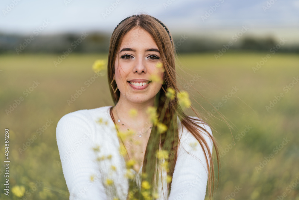 young woman showing some yellow flowers in a field young woman showing some yellow flowers in a field