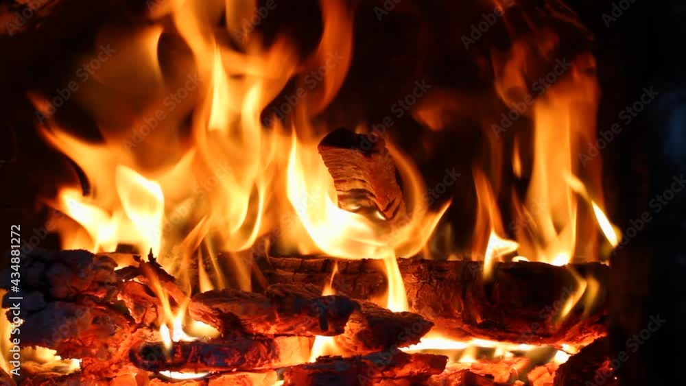 The firewood is burning brightly in the old stone stove. Sparks fly apart. Close-up. The firewood is burning brightly in the old stone stove. Sparks fly apart. Close-up.