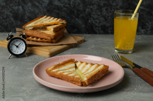 Concept of tasty breakfast with grilled sandwich on gray textured table