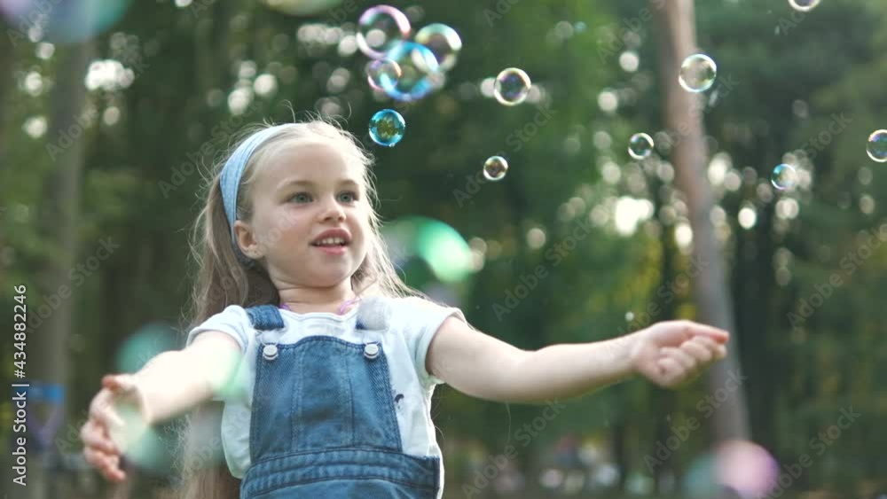 Little happy child girl chasing soap bubbles outdoors in summer park. Little happy child girl chasing soap bubbles outdoors in summer park.