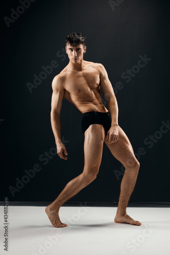 man with a pumped-up body holds his hands above his head posing dark panties