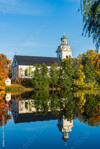 White church standing by a river with autumn colored trees