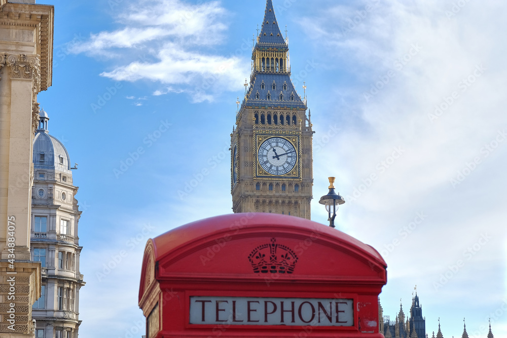typical red phone box on the streets of london with big ben looming behind, united kingdom