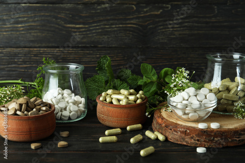 Concept of herbal medicine pills on wooden background