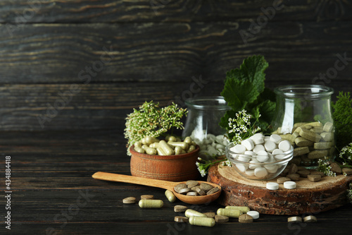 Concept of herbal medicine pills on wooden table, space for text