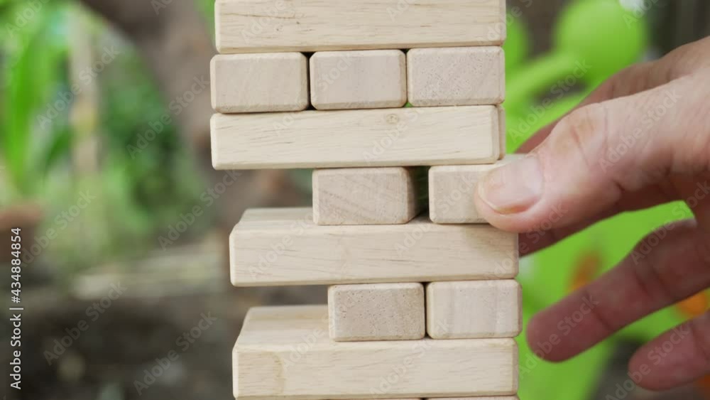 hands of man plays jenga on in the garden, close-up. A man builds a tower of blocks while playing jenga