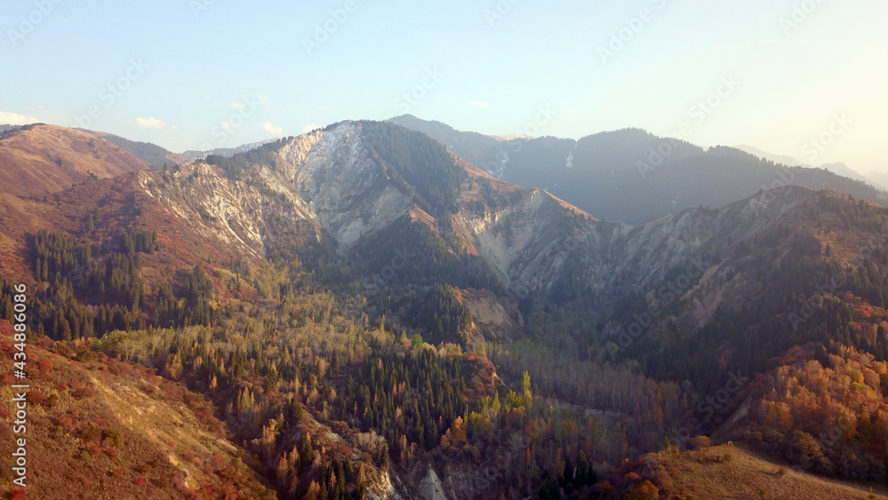 Autumn mountain forest. Top view from a drone. The bright colors of the trees. Green, orange, red, yellow - all colors. A mountain river is visible. There was a mudslide, a strong collapse of the rock Autumn mountain forest. Top view from a drone. The bright colors of the trees. Green, orange, red, yellow - all colors. A mountain river is visible. There was a mudslide, a strong collapse of the rock